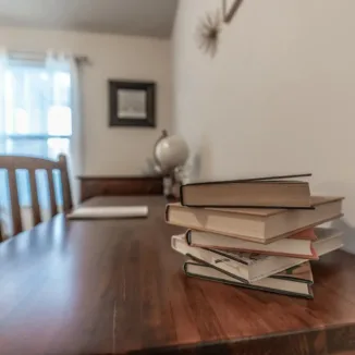 stacked books on a wooden desk